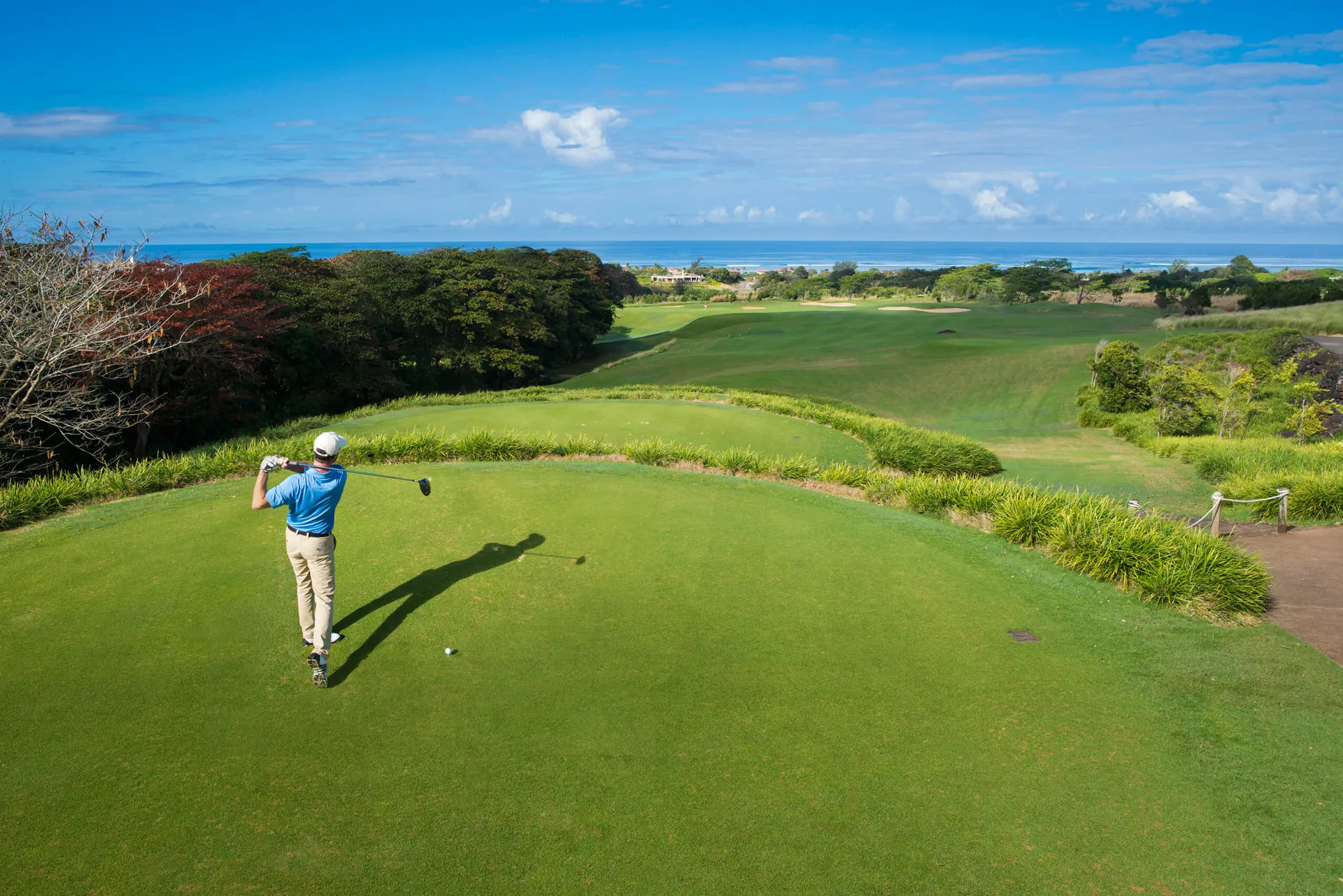 Golfer beim Abschlag auf einem Championship-Platz auf Mauritius mit Blick auf den Indischen Ozean